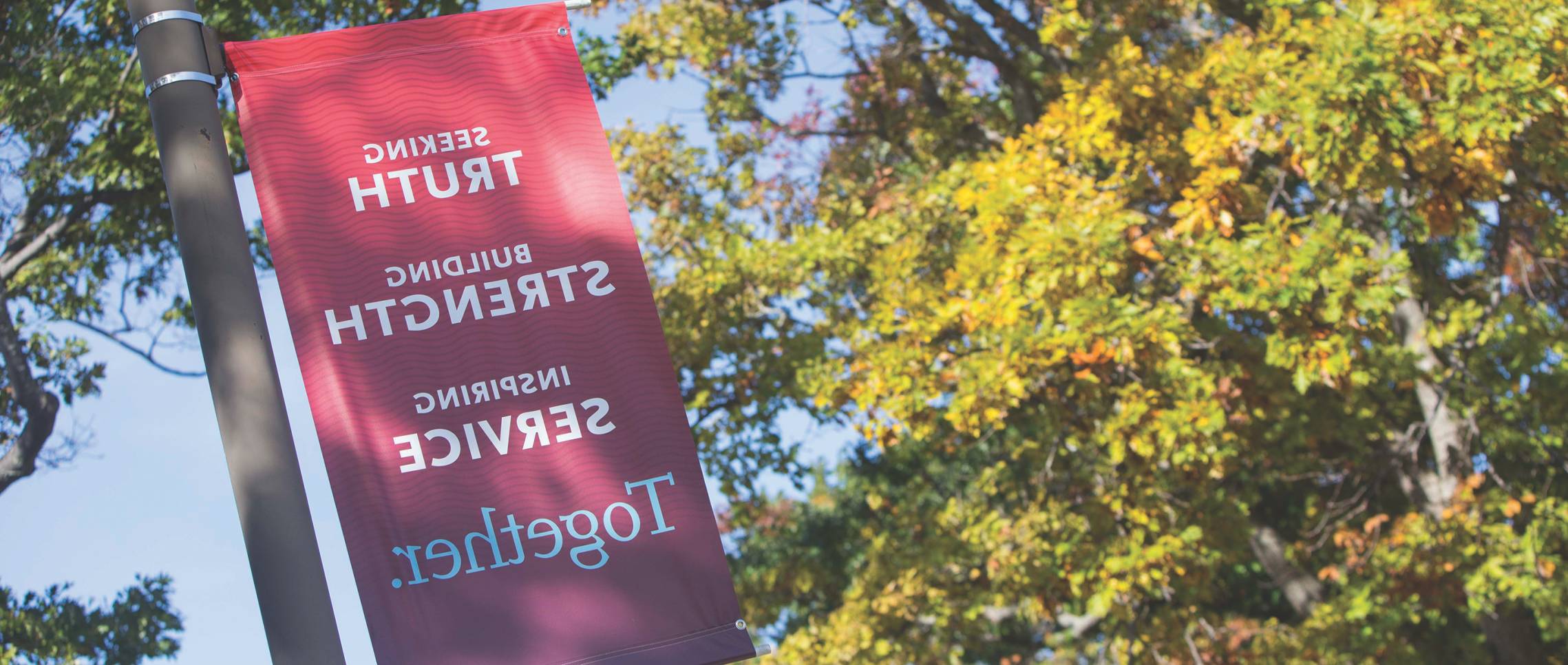 A banner on Campus Drive displays the Carthage College mission statement: Seeking Truth, Building Strength, Inspiring Service: Together.